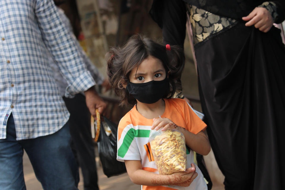 A girl wearing a protective face mask holds a bag of snacks during a curfew in response to the outbreak of the Coronavirus (COVID-19) pandemic on March 27, 2020 in Mumbai, India. (Photo by Himanshu Bhatt/NurPhoto via Getty Images)