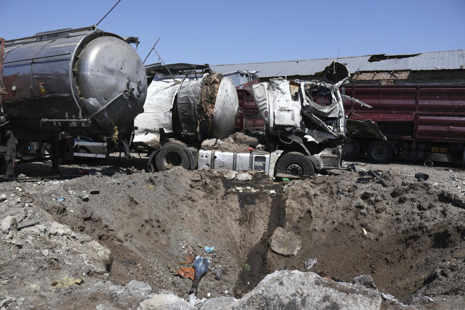 A crater is seen next to destroyed trucks after Russian shelling in Rozumivka, near Zaporizhzhia, Ukraine, Tuesday, June 20, 2023. (AP Photo/Andriy Andriyenko)