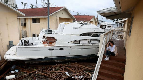 PHOTO: Brenda Brennan sits next to a boat that pushed against her apartment when Hurricane Ian passed through the area on Sept. 29, 2022 in Fort Myers, Fla. (Joe Raedle/Getty Images)