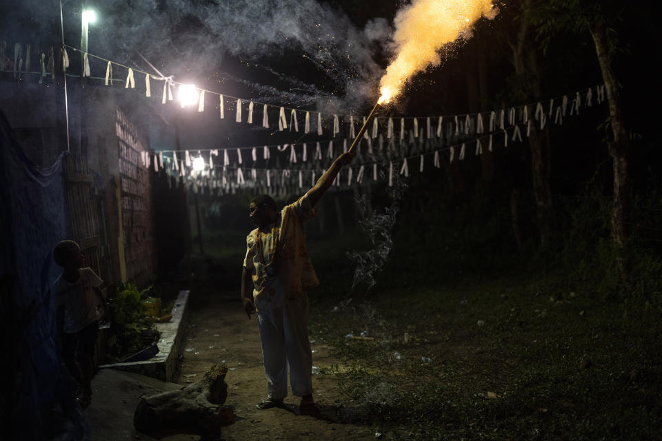 A devotee holds a flaming firework outside an Afro Brazilian faith Candomble temple during a ritual honoring the deity Obaluae on the outskirts of Salvador, Brazil, Saturday, Sept. 17, 2022. Today just a small minority practices Afro Brazilian religions. (AP Photo/Rodrigo Abd)