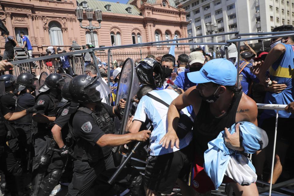 Soccer fans scuffle with police guarding the presidential palace, where Diego Maradona is lying in state, in Buenos Aires, Argentina, Thursday, Nov. 26, 2020. The Argentine soccer great who was among the best players ever and who led his country to the 1986 World Cup title died from a heart attack at his home Wednesday, at the age of 60. (AP Photo/Rodrigo Abd)