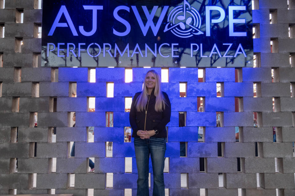 Wendy Swope, stands in front of the sign for the newly opened AJ Swope Performance Plaza honoring her late husband Friday night at the Arts in the Sunset in Amarillo.