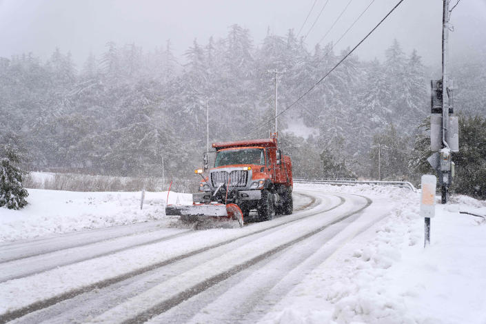 A plow clears snow on Mount Baldy Road in the city of Mount Baldy, California February 24, 2023. - Californians, who are more used to flip-flops and shorts, enveloped the warm Thursday in a rare winter blizzard, the first since more than 30 years ago, loomed over Los Angeles even as the US east coast basked in summer temperatures.  (Allison Dinner / AFP - Getty Images)