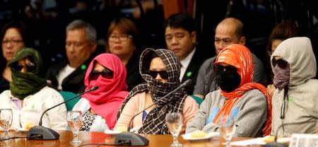 Family members of people alleged by police as drug pushers and were killed during an illegal drugs "meth raid", wear masks during a Senate hearing regarding people killed during a crackdown on illegal drugs in Pasay, Metro Manila, Philippines August 23, 2016. REUTERS/Erik De Castro