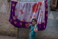 A girl waits outside her home to see if she and her family will get a carton filled with food from non-governmental organization Resala Nour Ala Nour, who are distributing aid to people who have been greatly affected by the coronavirus pandemic, in Cairo, Egypt, Thursday, April 9, 2020. (AP Photo/Nariman El-Mofty)