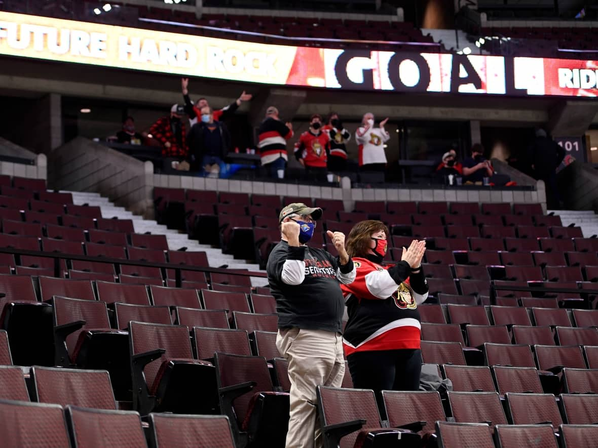 Fans celebrate the Ottawa Senators' overtime win against the Edmonton Oilers Jan. 31, 2022. The Senators announced a sell out game of 500 attendees, the maximum number of people permitted for sporting games at that time. (Justin Tang/The Canadian Press - image credit)