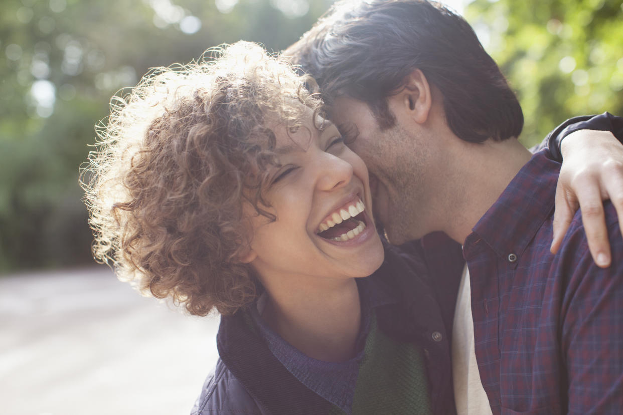 Man kissing woman's cheek as both laugh 