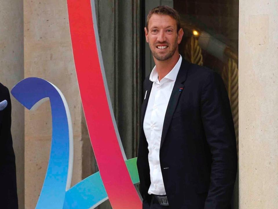 Alain Bernard poses next to the Paris 2024 sign.