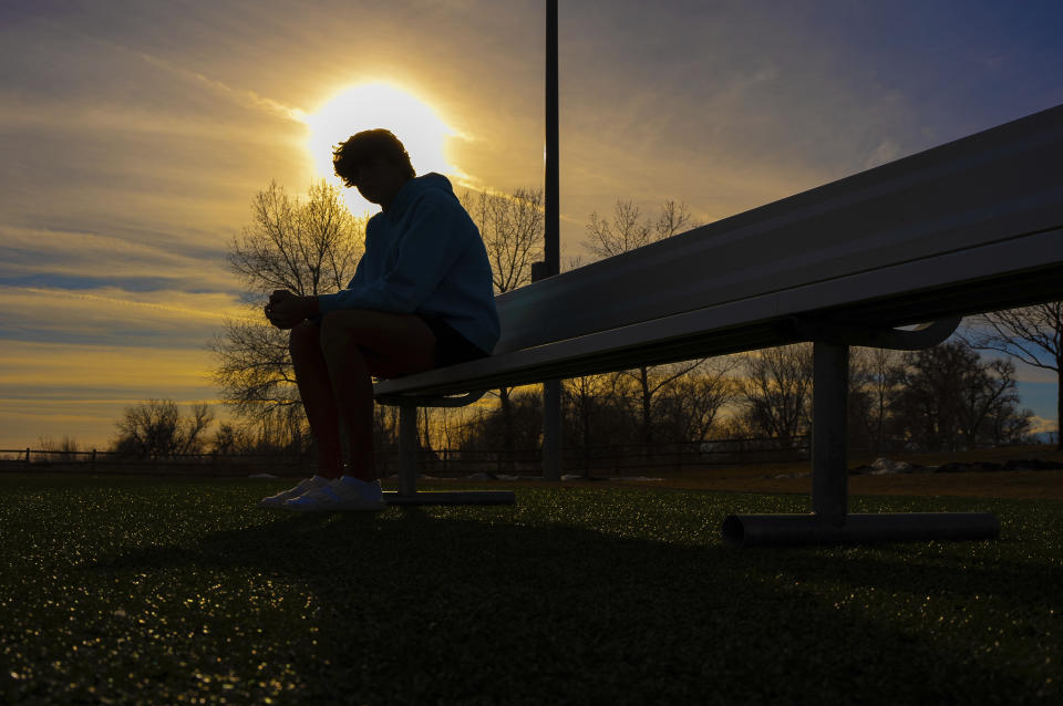 A 16-year-old swimmer sits on a bench at a park near his home about 40 miles north of Denver on Dec. 22, 2023. The Associated Press is not using the teen's name because he is a minor. A teammate accused the swimmer of slapping him on the butt in 2021. The U.S. Center for SafeSport opened an investigation nearly 10 months after the alleged incident and it remains open more than 20 months since it was first reported. The teen and his mother say their case is an illustration of an overwhelmed organization that received about 7,000 reports last year with only 65 people available to sort through and investigate them. (AP Photo/Jack Dempsey)