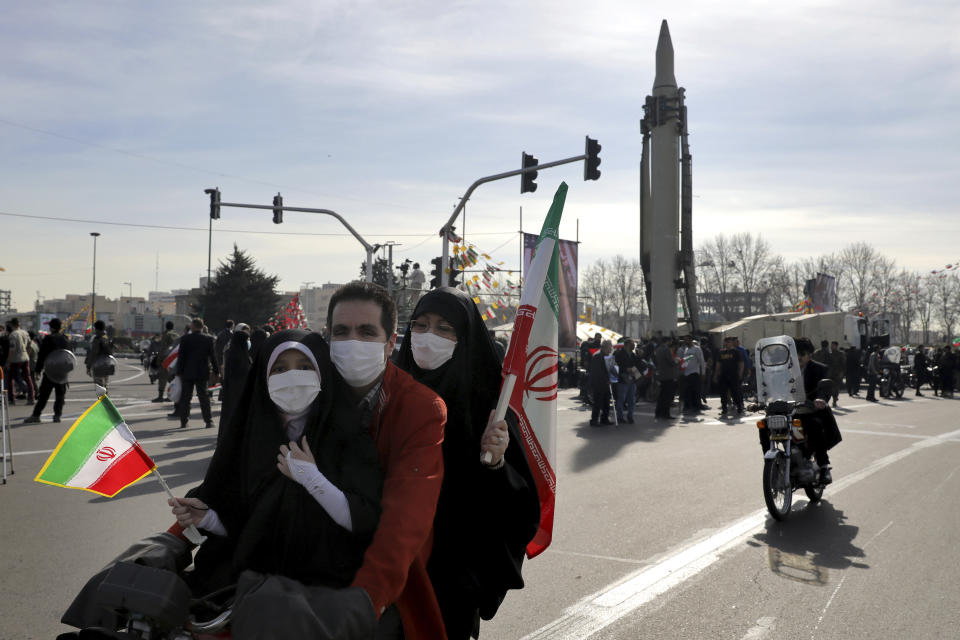 Iranians drive past a missile by their motorcycles during a rally marking the 42nd anniversary of the Islamic Revolution, at Azadi (Freedom) Square in Tehran, Iran, Wednesday, Feb. 10, 2021. Iranians Wednesday began a vehicle-only rallies in cities and towns across the country to mark the anniversary of its 1979 Islamic Revolution. The decision for replacing traditional rallies and demonstrations by vehicle-only move came as a measure to prevent spread of the coronavirus as the country struggles to stem the worst outbreak of the pandemic in the Middle East with death toll nearing 59,000 and some 1.48 million confirmed cases of the virus. The country on Tuesday launched a coronavirus inoculation campaign. (AP Photo/Ebrahim Noroozi)