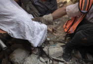 <p>En la imagen, un equipo de rescate de Palestina intenta sacar el cuerpo de una mujer de debajo de los escombros de una casa destruida por los ataques aéreos israelíes en la ciudad de Gaza. (Foto: Khalil Hamra / AP).</p> 