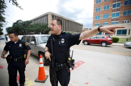 A Dallas police officer asks media to move away from in front of the Dallas Police Department headquarters which was locked down after an anonymous threat was reported in Dallas, Texas, U.S. July 9, 2016. REUTERS/Carlo Allegri