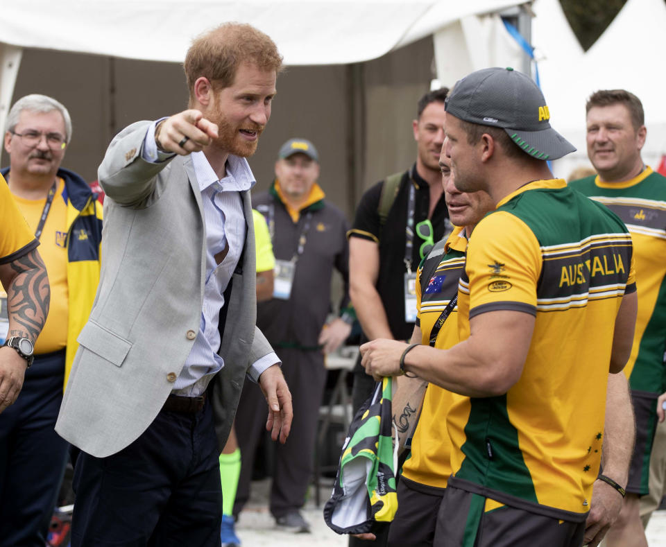 Britain's Prince Harry, left, meets Australian competitors who show him a pair of trunks as he attends the Invictus Games cycling competition at the Royal Botanic Garden in Sydney, Australia, Sunday, Oct. 21, 2018. Prince Harry and his wife Meghan are on day six of their 16-day tour of Australia and the South Pacific. (Paul Edwards/Pool Photo via AP)