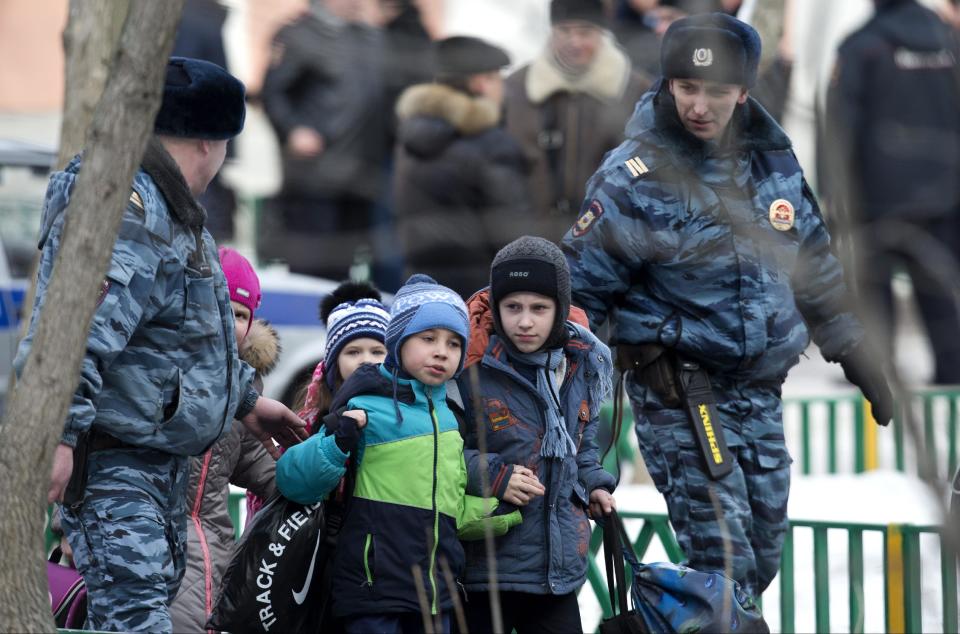 Police officers evacuate children from a Moscow school on Monday, Feb. 3, 2014. An armed teenager burst into his Moscow school on Monday and killed a teacher and policeman before being taken into custody, investigators said. None of the children who were in School No. 263 were hurt, said Karina Sabitova, a police spokeswoman at the scene. The student also wounded a second police officer who had responded to an alarm from the school, she said. (AP Photo/Alexander Zemlianichenko)