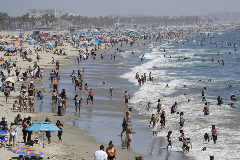 FILE - In this July 12, 2020, file photo, visitors crowd the beach in Santa Monica, Calif., amid the coronavirus pandemic. Californians headed to campgrounds, beaches and restaurants over the long holiday weekend as the state prepared to shed some of its coronavirus rules. (AP Photo/Marcio Jose Sanchez, File)