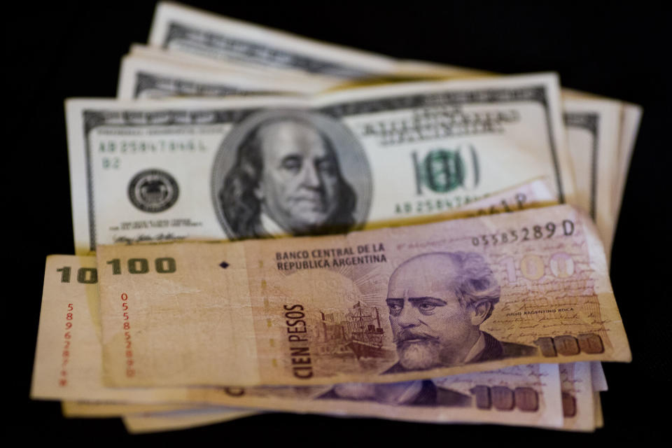 U.S. dollar bills and Argentine pesos are displayed for the photographer on a table at a currency exchange business in Buenos Aires, Argentina, Thursday, Jan. 23, 2014. Argentina's peso has plunged just over 17 percent in the last two days against the U.S. dollar, and economic analysts expect inflation to hit 30 percent this year. (AP Photo/Victor R. Caivano)
