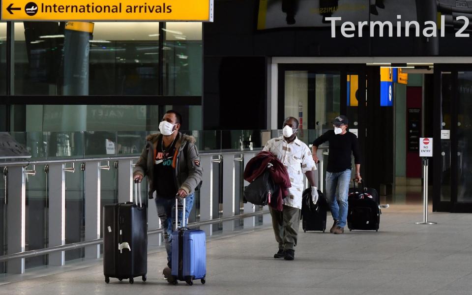 Passengers wearing PPE walk through the arrivals hall after landing at at Terminal Two of London Heathrow Airport - AFP