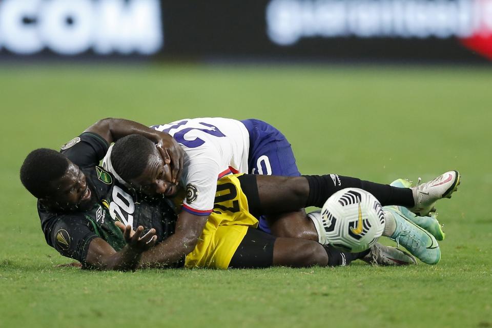 Jamaica defender Kemar Lawrence (20) is knocked down by United States defender Shaq Moore, top, as the two compete for control of the ball in the second half of a CONCACAF Gold Cup quarterfinals soccer match, Sunday, July 25, 2021, in Arlington, Texas. (AP Photo/Brandon Wade)