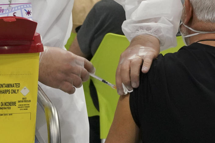 A man receives a dose of the Pfizer COVID-19 vaccine, at a vaccination center set at Rome's Cinecitta' film studios, Tuesday, April 20, 2021. (AP Photo/Andrew Medichini)