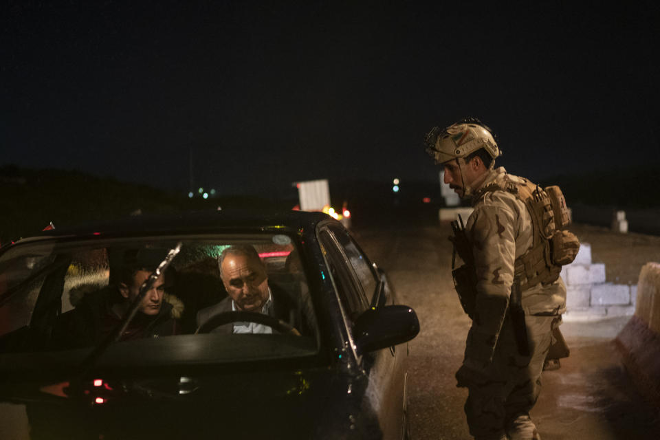 In this April 2, 2019 photo, an Iraqi army 20th division soldier asks for documents at a checkpoint near Badoush, Iraq. A year and a half after the Islamic State group was declared defeated in Iraq, the militants still evoke fear in the lands of their former so-called caliphate across northern Iraq. The fighters, hiding in caves and mountains, emerge at night to carry out kidnappings, killings and roadside ambushes, aimed at intimidating locals, silencing informants and restoring the extortion rackets that financed IS's rise to power six years ago. (AP Photo/Felipe Dana)