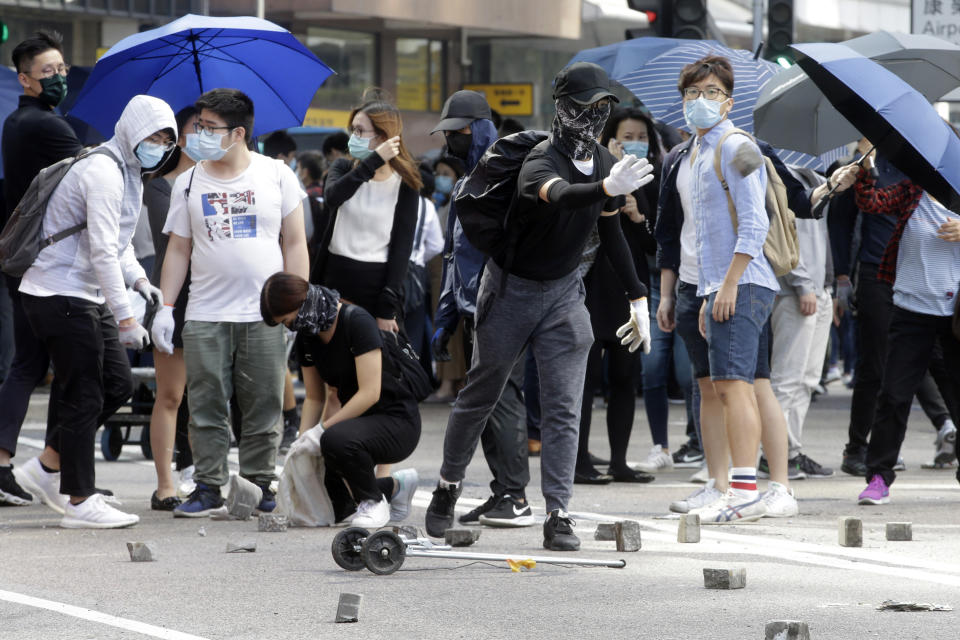 Demonstrators toss bricks onto a road to create a traffic barricade during a protest in the financial district in Hong Kong, Friday, Nov. 15, 2019. Protesters who have barricaded themselves in a Hong Kong university partially cleared a road they were blocking and demanded that the government commit to holding local elections on Nov. 24. (AP Photo/Achmad Ibrahim)