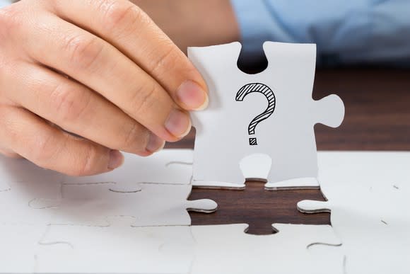 Man holding jigsaw puzzle piece with question mark on it