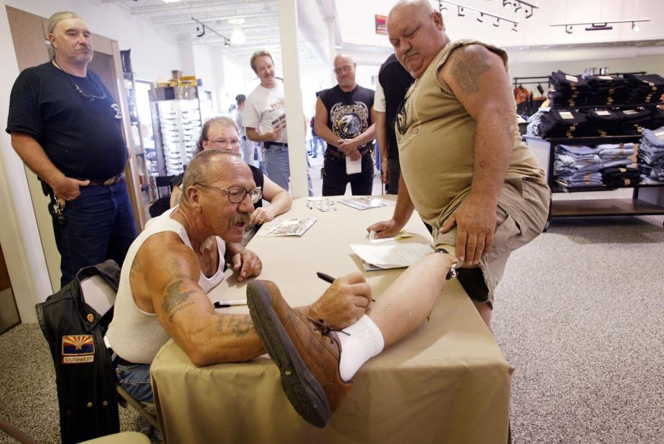 Sonny Barger, founder of the Oakland, California charter of the Hells Angels motorcycle club, autographs the artificial leg of Kenny Little during an event at a Harley-Davidson motorcycle dealership August 23, 2003 in Quincy, Illinois. Little lost his leg when his motorcycle was hit by a drunk driver in 1986.