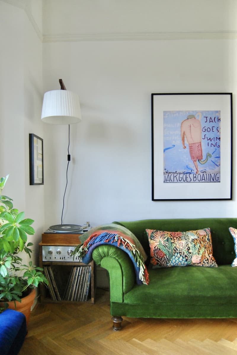 Living room with green velvet couch flanked by a record player.