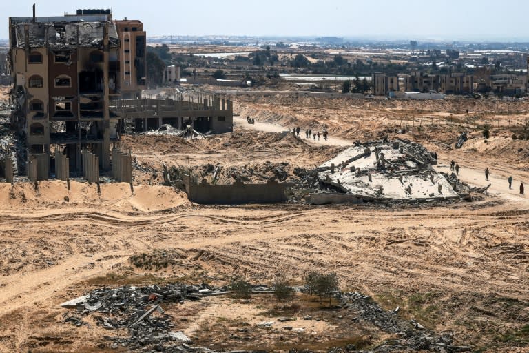 Des Palestiniens marchent au milieu de bâtiments endommagés ou détruits à Khan Younès après le retrait des troupes israéliennes de cette ville du sud de la bande de Gaza, le 7 avril 2024 (MOHAMMED ABED)