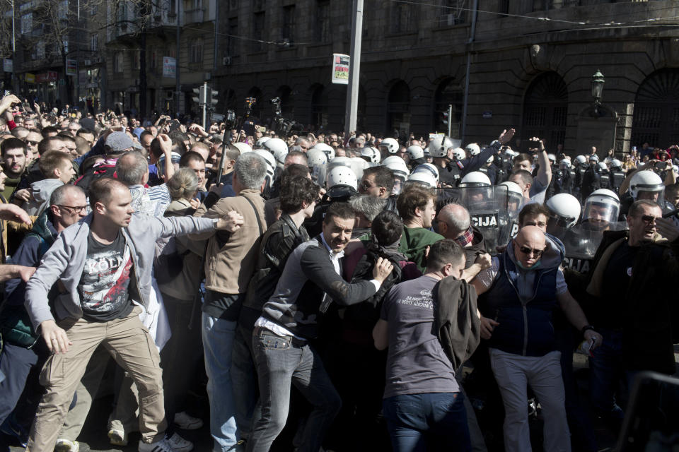 A group of protesters push a cordon of riot police in Belgrade, Serbia, Sunday, March 17, 2019. As Serbian president Aleksandar Vucic held a news conference in the presidency building in downtown Belgrade, thousands of opposition supporters gathered in front demanding his resignation. Skirmishes with riot police were reported, including officers firing tear gas against the protesters who have pledged to form a human chain around the presidency to prevent Vucic from leaving the building. (AP Photo/Marko Drobnjakovic)