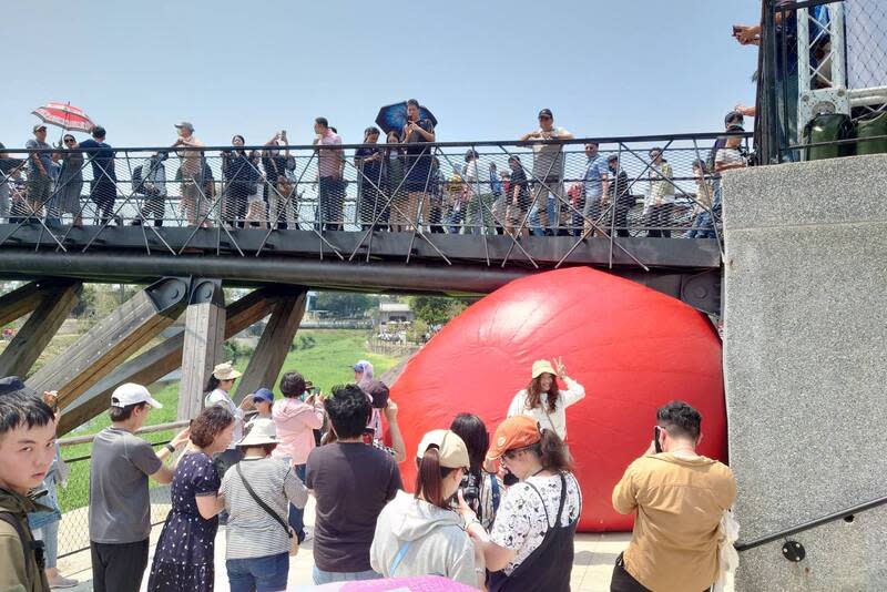 紅球台南歷史街區策展行動6日移展竹溪水岸園區月 見橋，「塞」在橋下步道與支架間，現場湧入不少民 眾與紅球近距離互動拍照。 中央社記者楊思瑞攝  113年4月6日