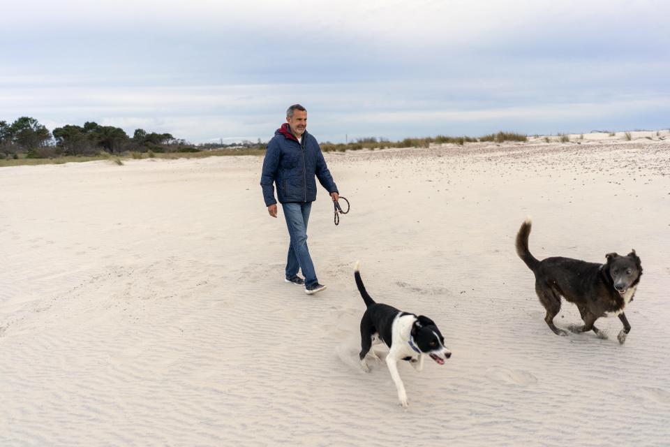 Federico Van Geldern, un ciudadano argentino que vive en un balneario llamado Solís, en Uruguay, camina con sus perros en la playa el martes 15 de septiembre de 2020. Desde que la pandemia del nuevo coronavirus empezó hace más de seis meses, miles de argentinos como Van Geldern decidieron permanecer y vivir en Uruguay. (AP Photo/Matilde Campodónico)