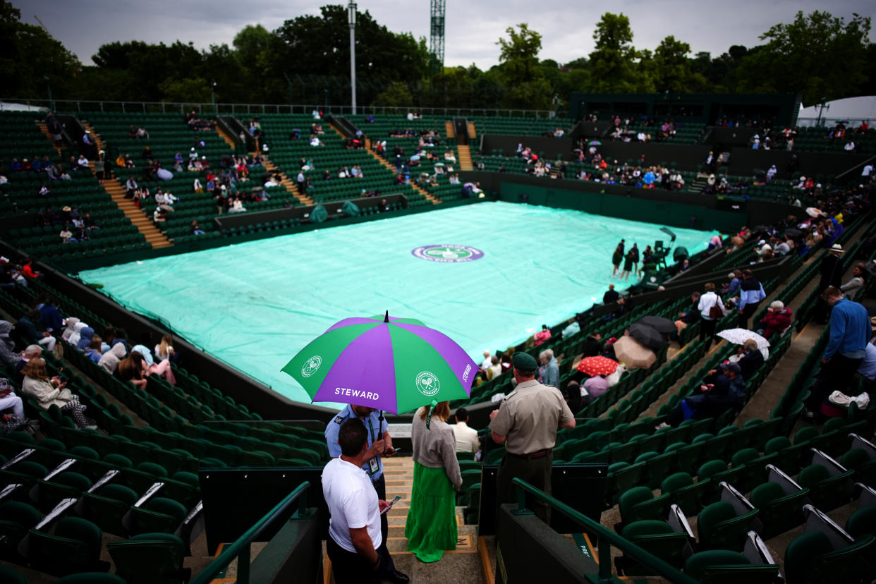 Spectators shelter from the rain on day three of the 2024 Wimbledon Championships in London. (PA/Getty)