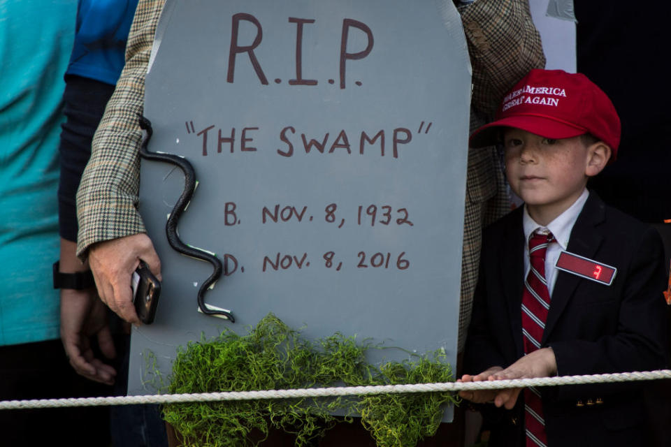 A boy dressed up as the president next to headstone that reads “R.I.P. ‘the swamp.'” at the White House. (Photo: Getty Images)