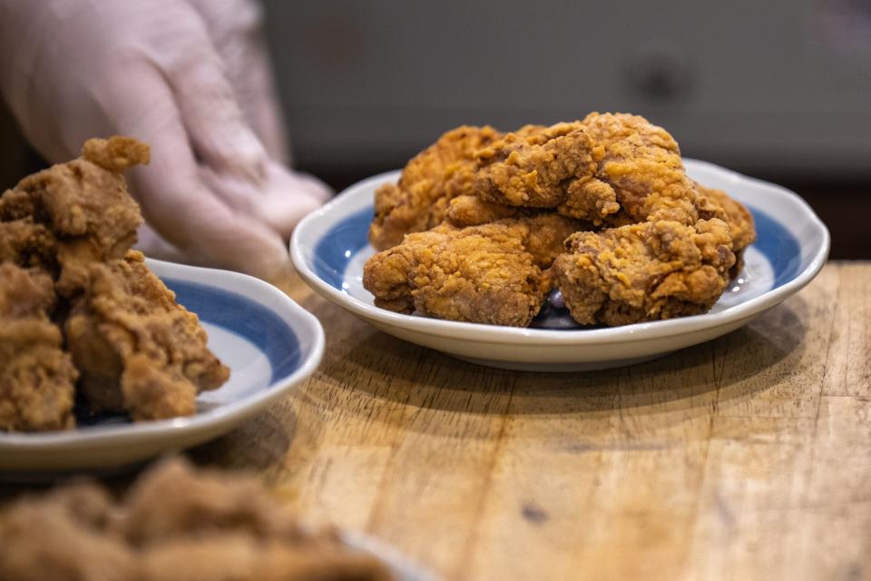 Plate of fried chicken on a wooden surface with another plate in the background