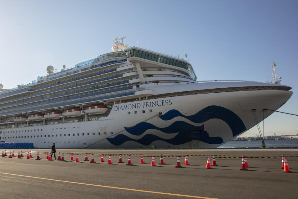 FILE - In this Feb. 11, 2020, file photo, a reporter walks near the quarantined Diamond Princess cruise ship in Yokohama, near Tokyo. Life on board the luxury cruise ship, which has dozens of cases of a new virus, can include fear, excitement and soul-crushing boredom, according to interviews by The Associated Press with passengers and a stream of tweets and YouTube videos. (AP Photo/Jae C. Hong, File)