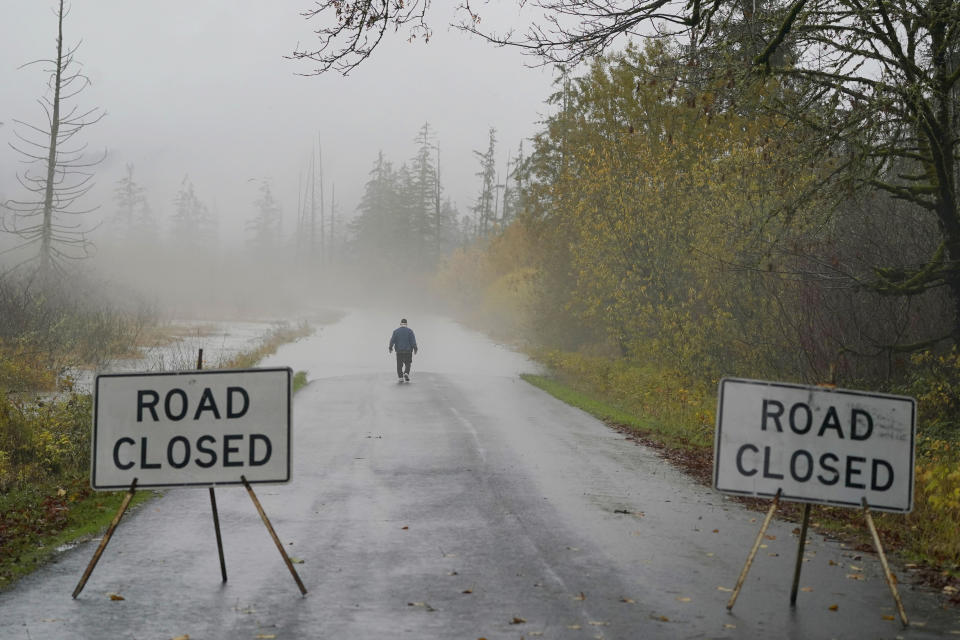 Clyde Shew, of Snoqualmie, Wash., checks out a section of W. Snoqualmie River Rd. NE that was closed due to high water conditions from the Snoqualmie River, Friday, Nov. 12, 2021, near Carnation, Wash. Flood watches and warnings were in place across the Northwest and forecasters said storms caused by an atmospheric river, known as the Pineapple Express and rain were expected to remain heavy in Oregon and Washington through Friday night. (AP Photo/Ted S. Warren)