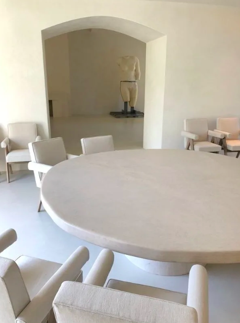 A minimalist circular dining table with matching neutral chairs and walls