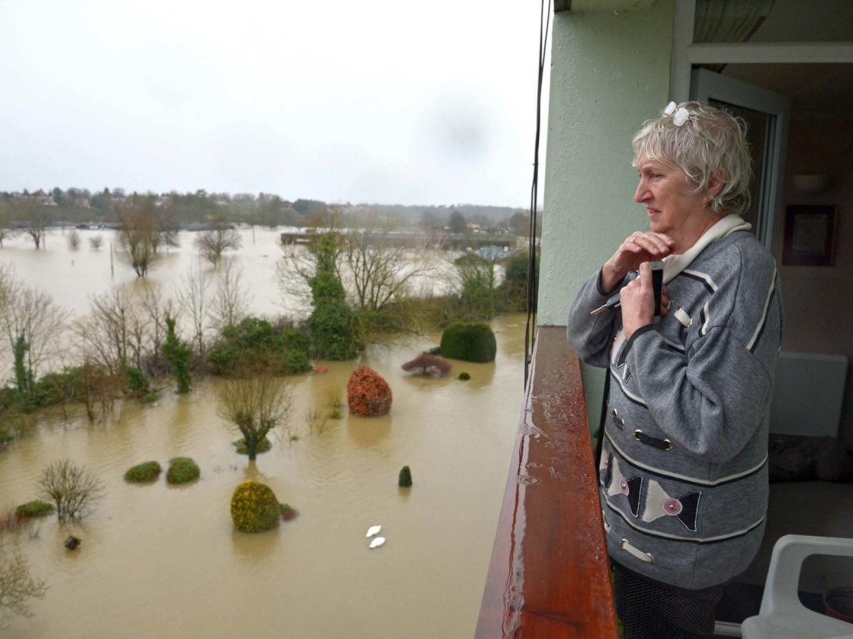 A resident living in a flat near the River Severn in Shrewsbury looks out over flooded gardens: PA