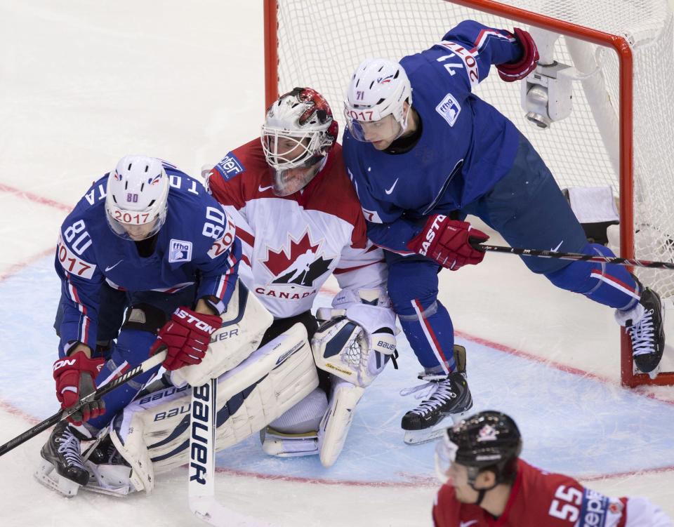 Team Canada goalie James Reimer gets squeezed between Team France Teddy Da Costa, left, and Anthony Guttig during second period action Friday, May 9, 2014 at the IIHF World Hockey Champiosnhip in Minsk Belarus. (AP Photo/The Canadian Press, Jacques Boissinot)