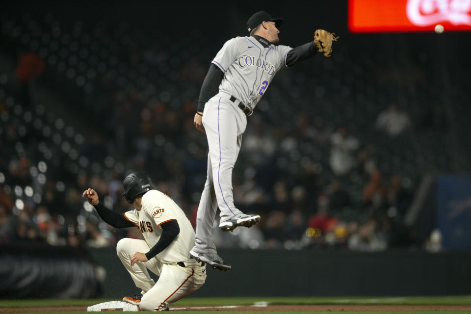 San Francisco Giants' Wilmer Flores (41) slides safely into third base as the relay sails high over the head of Colorado Rockies third baseman Ryan McMahon (24) during the sixth inning of a baseball game, Monday, May 9, 2022, in San Francisco. Flores scored on the error. (AP Photo/D. Ross Cameron)