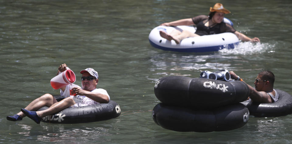 In a May 28, 2012 photo, a man, left, pours himself a beverage from a pitcher while floating down the Comal River in New Braunfels, Texas on Memorial Day. Drinking beer while lazily floating through New Braunfels is a heat-beating tradition for hundreds of thousands of vacationers each summer, but turnout is down and businesses say the reason is clear: a new ban on disposable containers. The so-called can ban doesn’t prohibit alcohol, but that message hasn’t been sticking. (AP Photo/San Antonio Express-News, John Davenport) MAGS OUT NO SALES SAN ANTONIO OUT