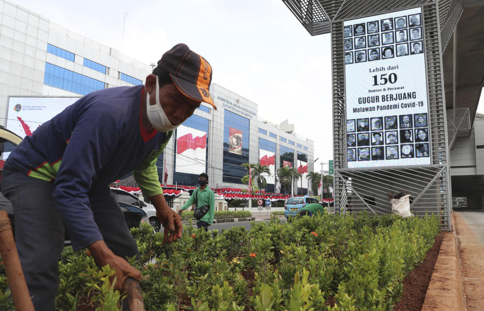 A man works near a monitor screen which honors health workers in Jakarta, Indonesia, Thursday, Sept. 17, 2020. Writings on the monitor read "More than 150 doctors and nurses have died battling the COVID-19 pandemic." (AP Photo/Achmad Ibrahim)