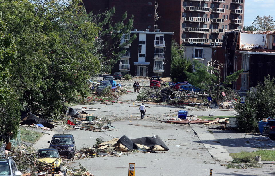 <p>People walk past debris in a Gatineau, Que. neighbourhood on Saturday, September 22, 2018. A tornado on Friday afternoon tore roofs off of homes, overturned cars and felled power lines in the Ottawa community of Dunrobin and in Gatineau, Que. (Photo from Fred Chartrand/The Canadian Press) </p>