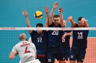 <p>(L-R) Canada's Nicholas Hoag hits the ball in front of Poland's Fabian Drzyzga, Mateusz Bieniek and Michal Kubiak in the men's preliminary round pool A volleyball match between Poland and Canada during the Tokyo 2020 Olympic Games at Ariake Arena in Tokyo on August 1, 2021. (Photo by Anne-Christine POUJOULAT / AFP)</p> 