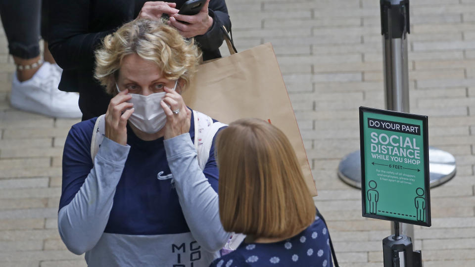 FILE - IIn this May 22, 2020, photo, women wait in line as they stand next to a social distancing sign in front of Cotton On, at City Creek Center, in Salt Lake City. Utah is seeing a spike in new COVID-19 cases about a month after many businesses were allowed to reopen, leading state health officials to issue renewed pleas for people to maintain social distancing. (AP Photo/Rick Bowmer, File)