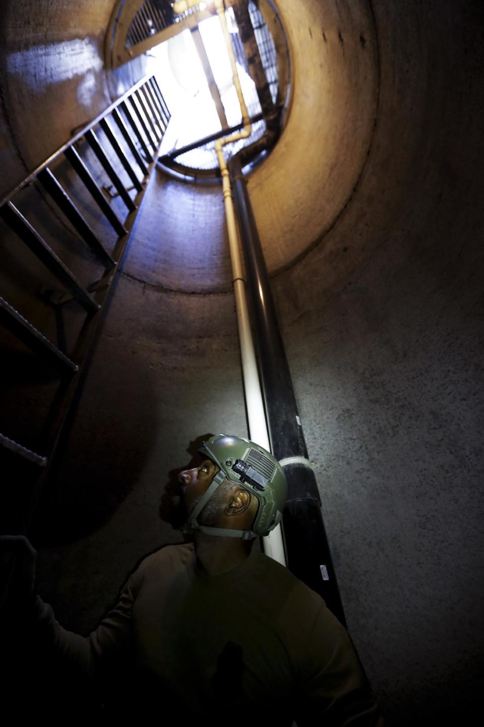 In this March 6, 2017 photo, a member of the Border Patrol's Border Tunnel Entry Team looks up as he descends an entrance carved out by the Border Patrol leading to a tunnel spanning the border between San Diego and Tijuana, Mexico, in San Diego. Authorities have discovered more than 200 cross-border tunnels originating in Mexico since 1990, most of which entered the United States. (AP Photo/Gregory Bull)