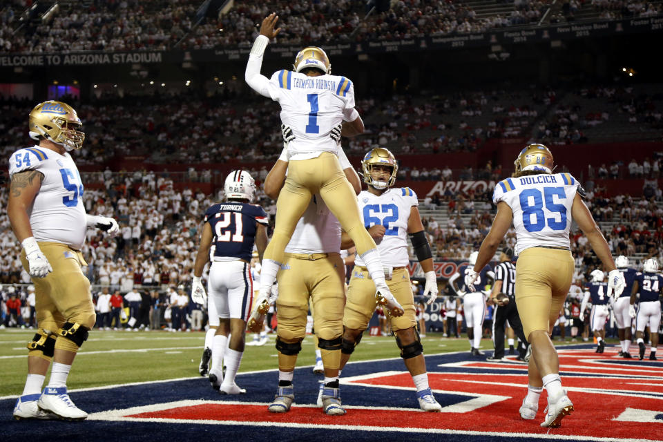 UCLA quarterback Dorian Thompson-Robinson (1) is hoisted after his rushing touchdown during the third quarter against Arizona in an NCAA college football game Saturday, Oct. 9, 2021, in Tucson, Ariz. (AP Photo/Chris Coduto)