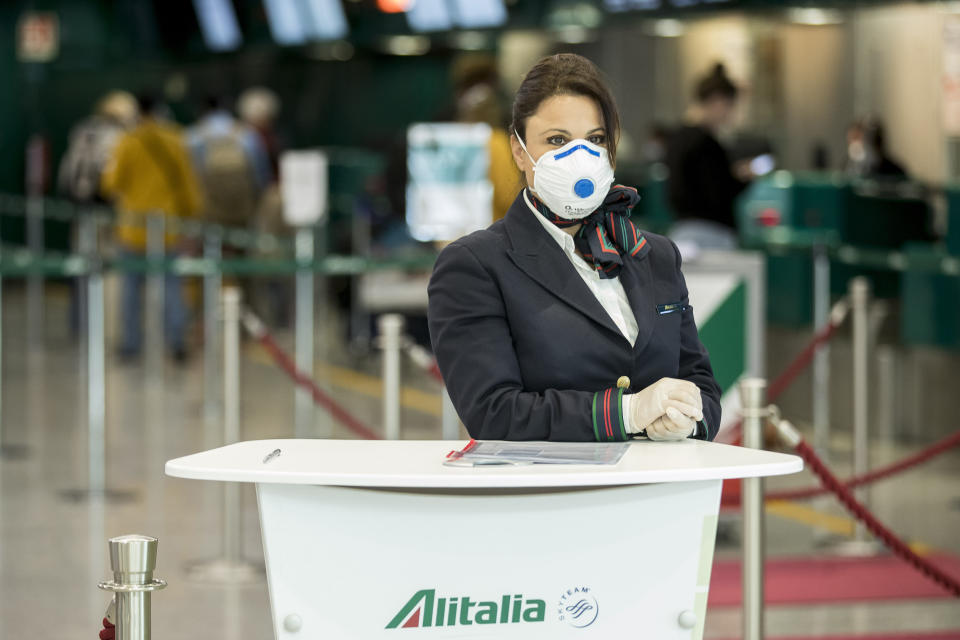 An Alitalia employee waits at the desk the Leonardo Da Vinci airport, in Rome, Tuesday, March 17, 2020. For most people, the new coronavirus causes only mild or moderate symptoms. For some it can cause more severe illness, especially in older adults and people with existing health problems.(Roberto Monaldo/LaPresse via AP)