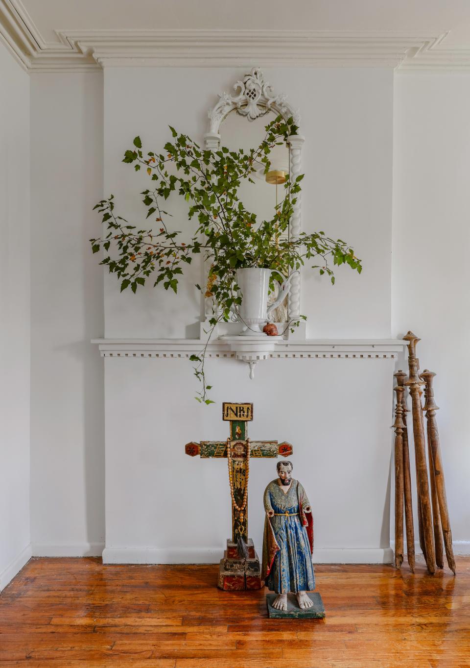 The fireplace mantel is another detail Mikey fought to save, turning it into a small sanctuary of antique finds and a rare arrangement of simple branches and ivy in an Astier de Villate vase.